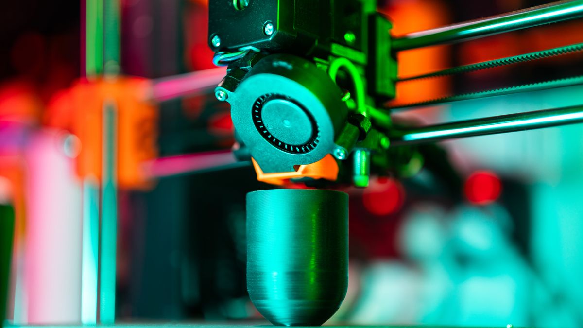 Close-up of a 3D printer creating a product in neon lighting.