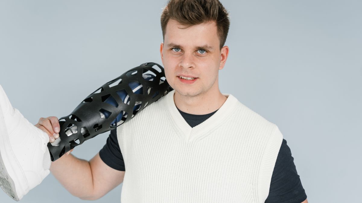A young adult holding a modern prosthetic leg during a studio photo shoot.