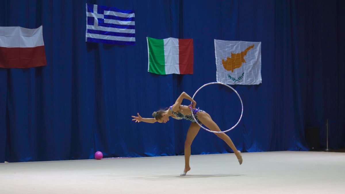 Dynamic image of a gymnast performing with a hoop on an international stage.