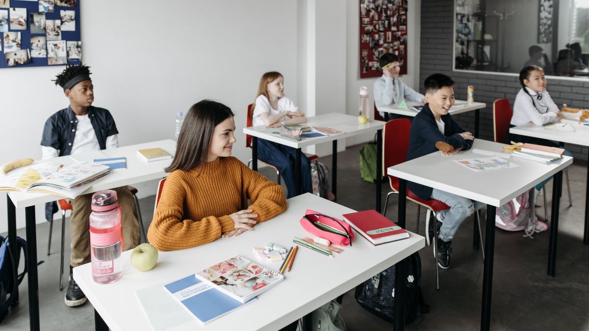 Students engage in a diverse classroom setting, collaborating at desks with educational materials.
