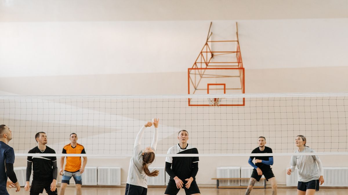 Adults playing an intense indoor volleyball game. Perfect depiction of sportsmanship and teamwork.