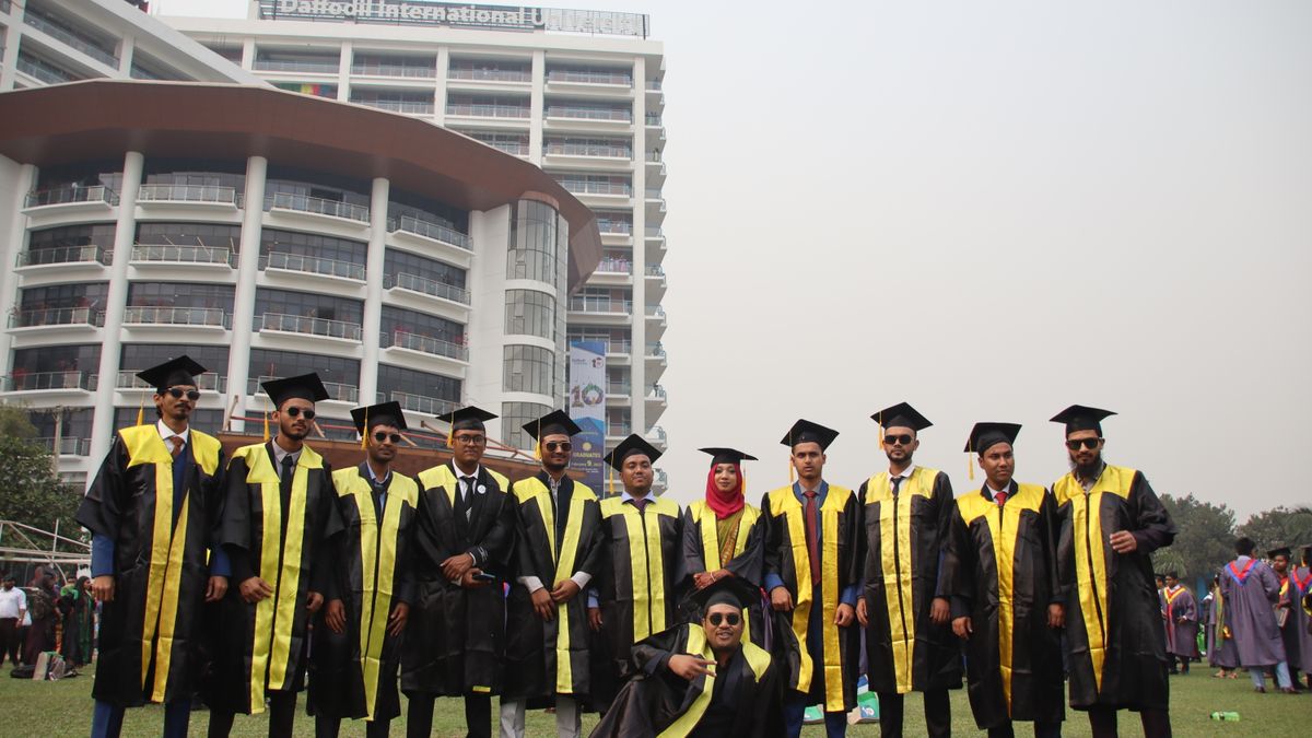 Graduating students celebrating with friends in front of university building.