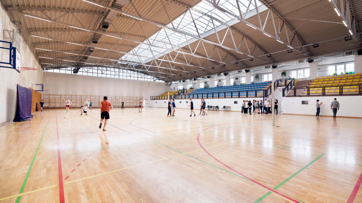 Wide-angle view of an indoor basketball court with players practicing and engaging in sports activities.